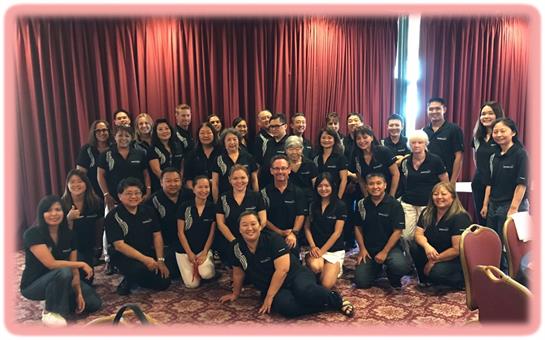 A group of smiling professionals in matching shirts poses together at a team-building event.