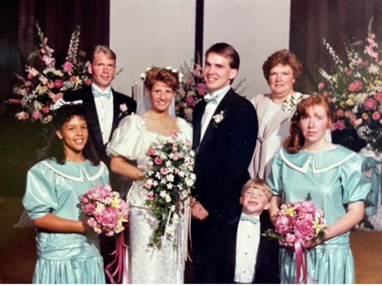 Family joyfully celebrates a wedding, featuring vibrant outfits and floral displays.