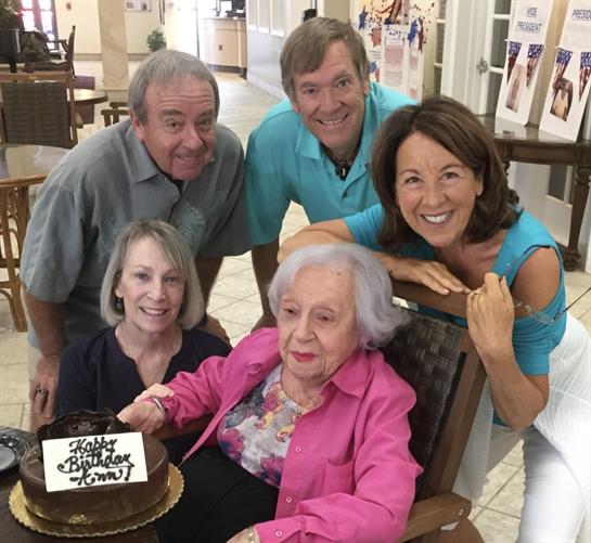 Loved ones gather to joyfully celebrate an elderly woman's birthday with cake and smiles.