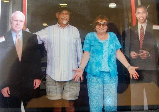 Four friends stand together, smiling and enjoying their time outside a store on a warm day.