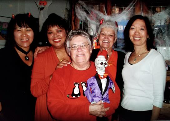 Women enjoy a Halloween-themed event, dressed festively with a skeleton decoration in hand.