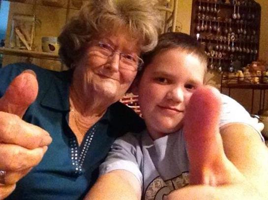 Grandmother and grandson happily give a thumbs up at home in the evening.