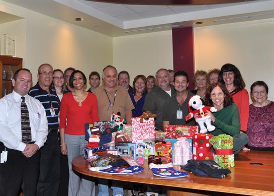 Employees gather around a table filled with wrapped gifts celebrating togetherness and joy.