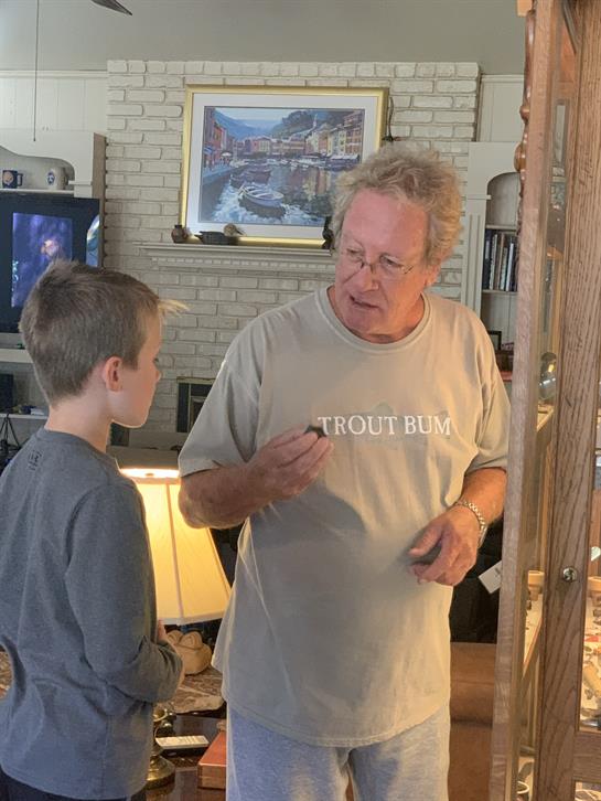 An older adult speaks with a young boy in a warm living room, sharing a moment together.