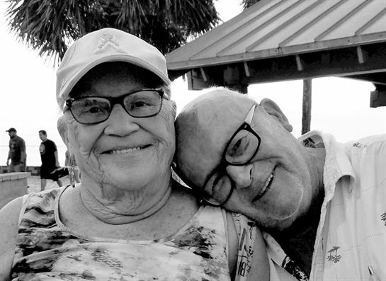 Two smiling seniors share a warm embrace and laughter while enjoying their time outdoors.