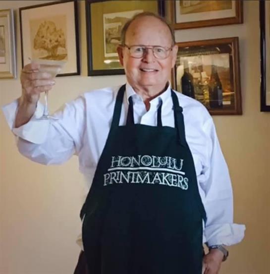 A cheerful man holds a glass, showing his love for art in a gallery of framed pieces.