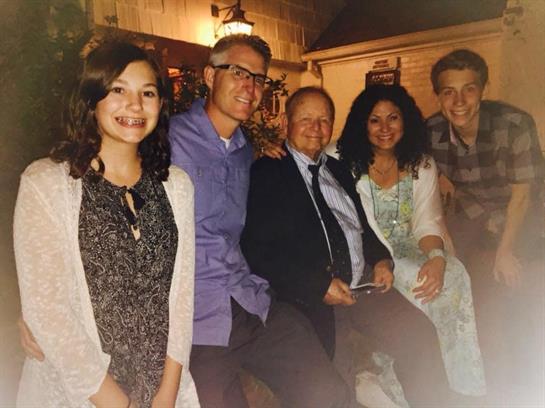 Five people sit together, smiling and enjoying a cozy evening.