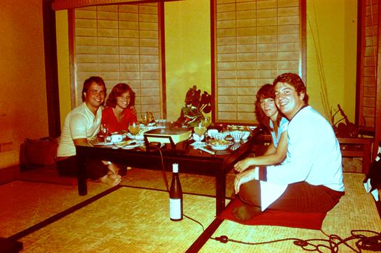 A group of four friends shares a joyful dinner around a traditional table.