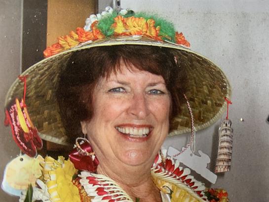 Cheerful woman dressed in vibrant floral attire enjoys a lively celebration with decorations.