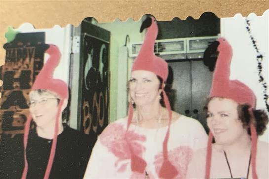 Women enjoy a playful moment together wearing bright flamingo hats at a lively event.