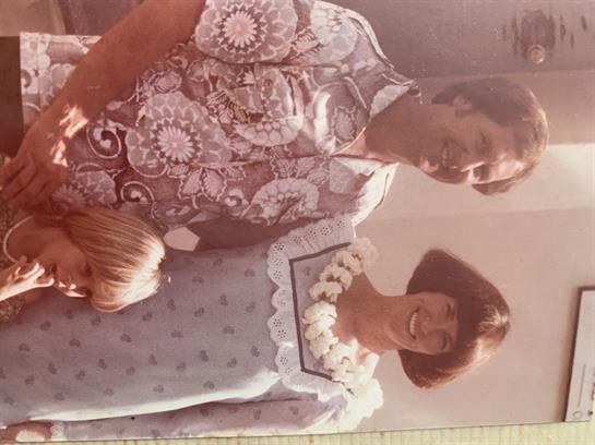 A family group stands together outdoors, smiling with relaxed expressions in vintage attire.