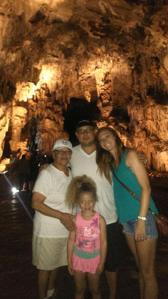 A family enjoys their visit near stunning illuminated cave rock formations.