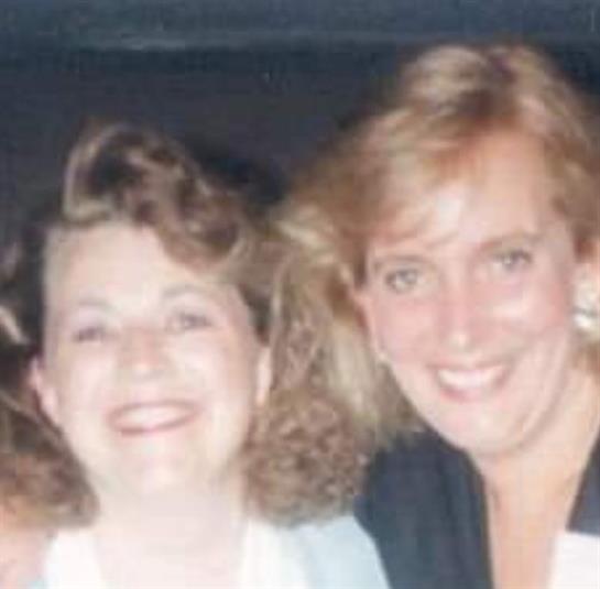 Two cheerful women pose closely, sharing laughter and friendship in a lively setting.