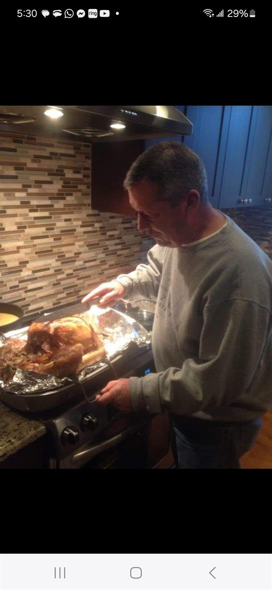 A man carves a roast dinner in a stylish kitchen setting, showcasing culinary skills.