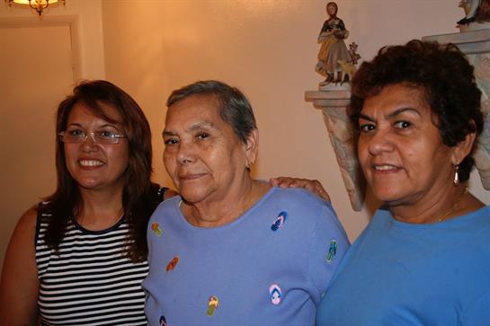 Three women smile happily, showcasing a family connection in a comforting indoor setting.