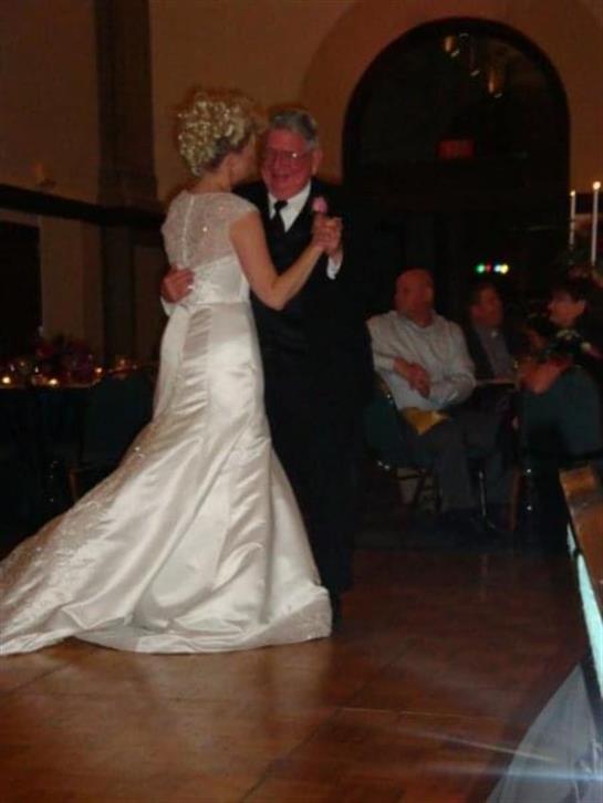 A bride and her partner enjoy their intimate first dance in a beautifully decorated venue at night.