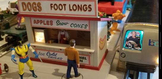 A vendor serves customers at a vibrant footlong stand crowded with joyful visitors.