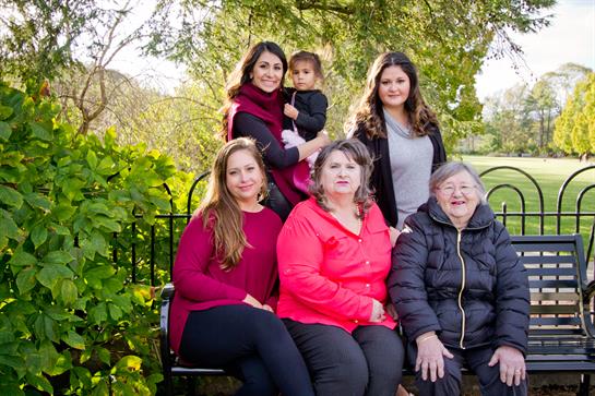 Several generations of women pose together outdoors, showcasing love and connection in the park.