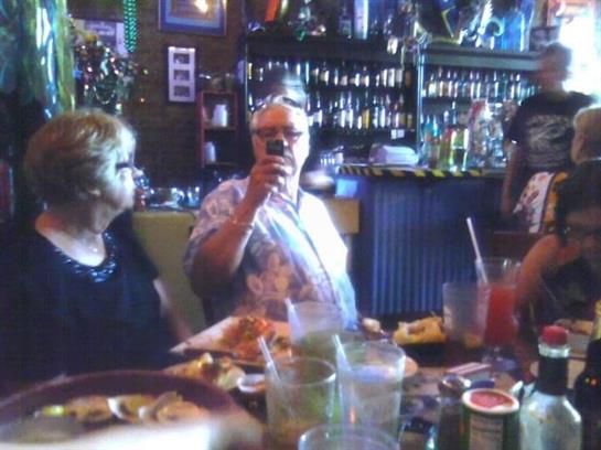 Group of friends enjoying food and drinks while celebrating at a bustling restaurant.