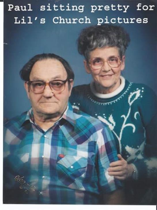 An elderly couple smiles warmly while standing together in a portrait setting with soft lighting.