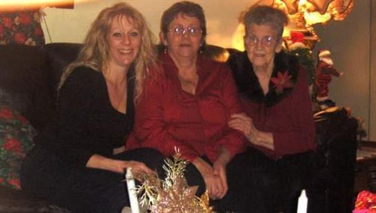Three women sit close together on a couch, celebrating with warmth and laughter during the holidays.