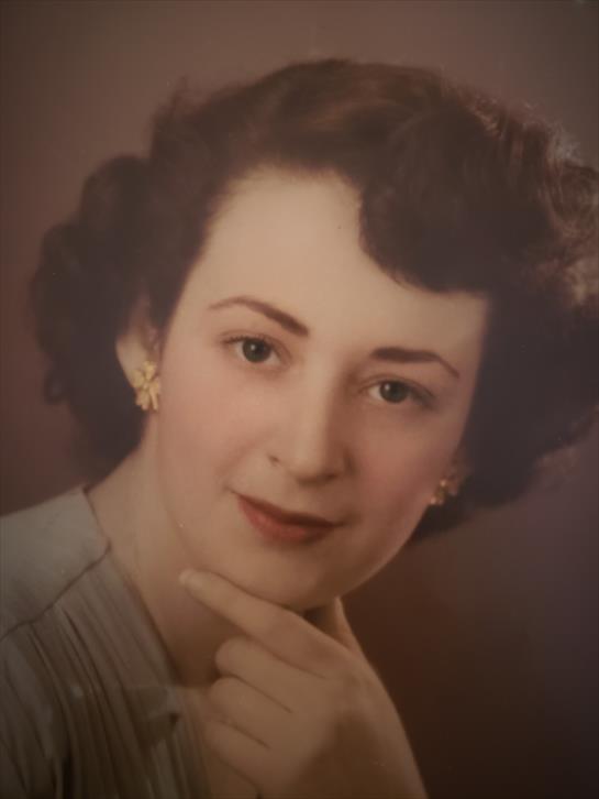 A young woman poses with a soft expression, highlighting her vintage hairstyle and elegant dress.