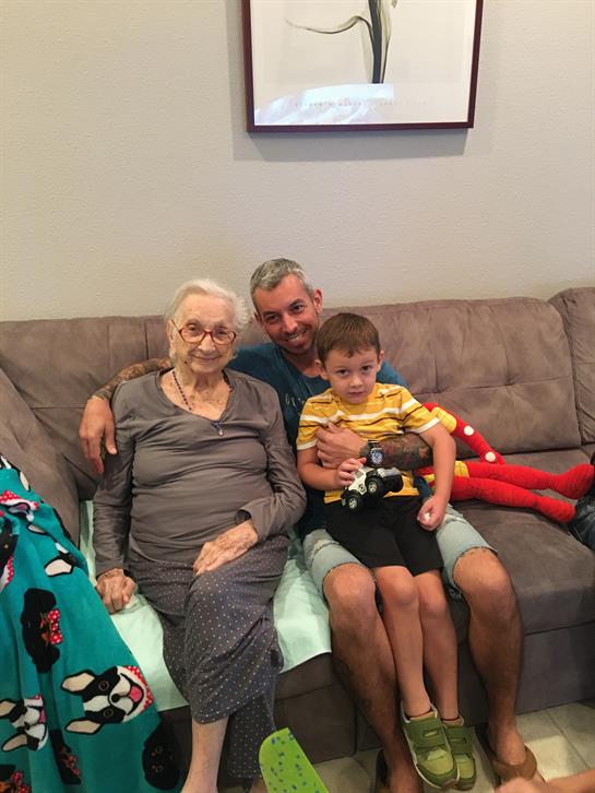 Three family members share a joyful moment on a comfortable couch, showcasing love and connection.
