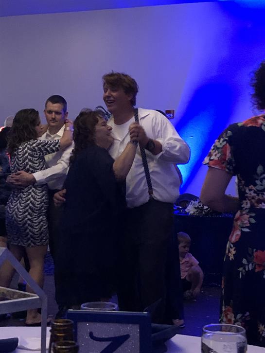 People dance joyfully while celebrating an occasion in a vibrant indoor venue with blue lighting.