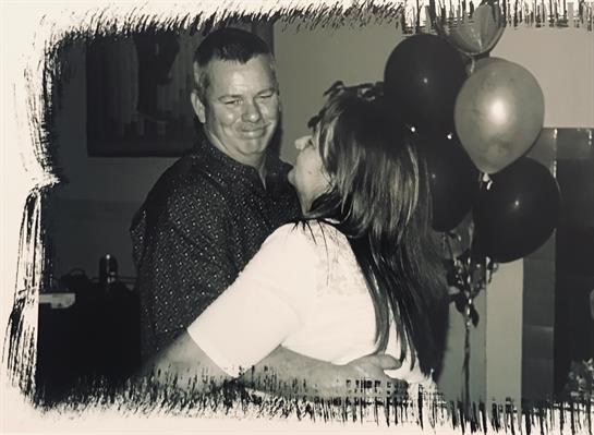A couple dances happily, celebrating a special moment amid balloons and decorations.