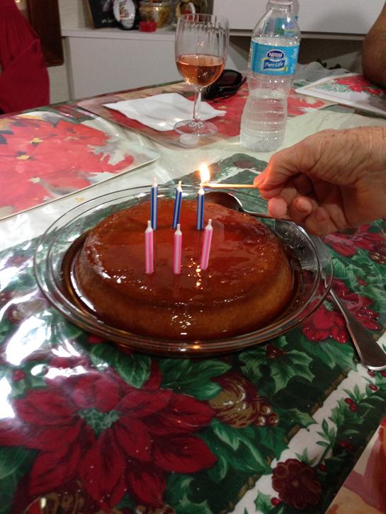A hand lights candles on a sweet dessert while friends gather to celebrate a joyful occasion.