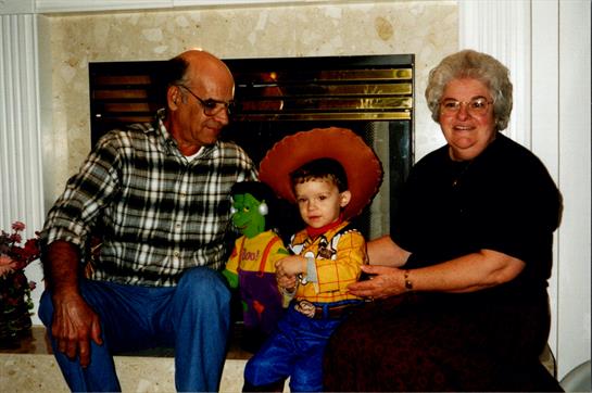 A joyful family moment with a young child in a cowboy outfit celebrating with grandparents.