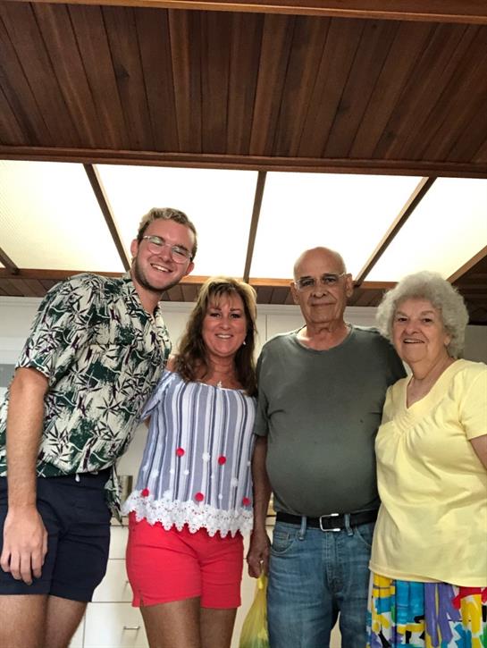 Group of four family members smiling together in a cozy home setting during a warm afternoon.