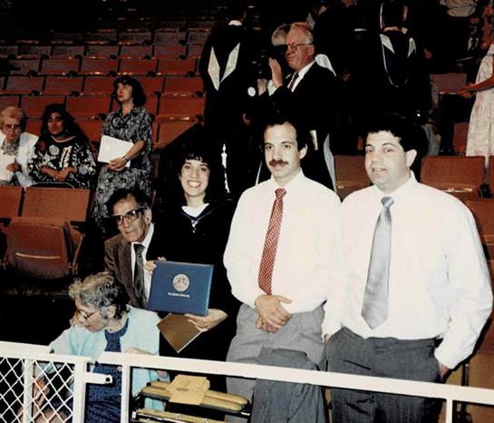 Group of people celebrating a graduation achievement in a packed auditorium during daylight.