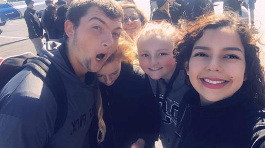 Group of young people smiling and having fun together outdoors under bright sunlight.