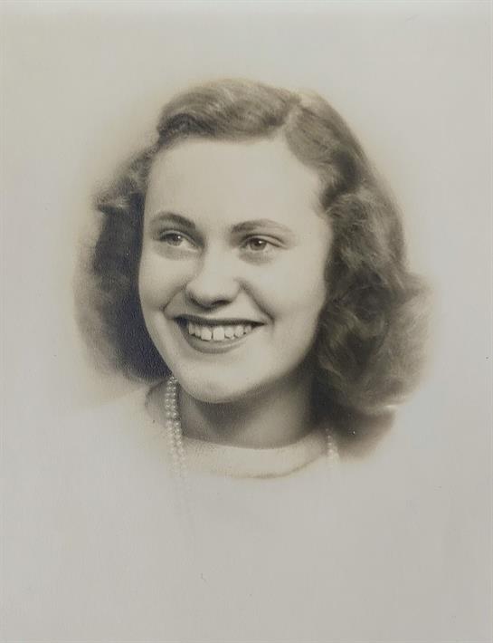 Portrait features a cheerful young woman with curly hair and a warm smile, radiating happiness.