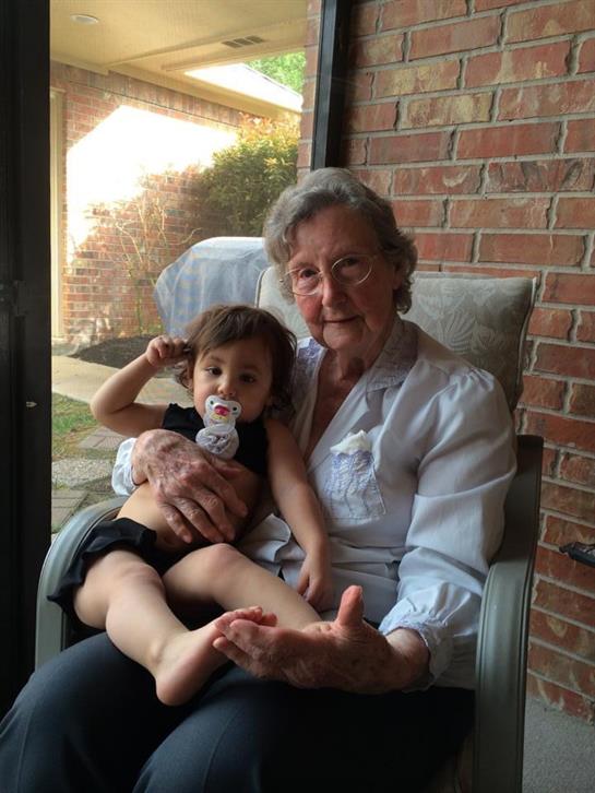 A grandmother holds her grandchild in a cozy chair while sharing a joyful moment indoors.