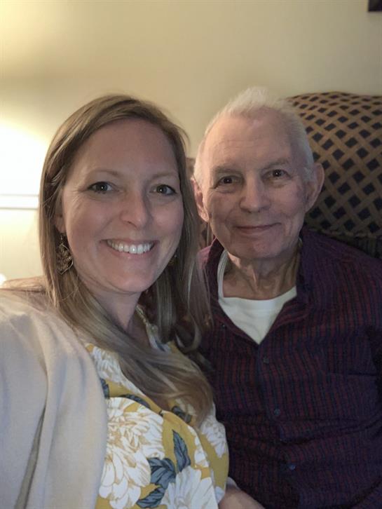 A woman and an elderly man share a joyful moment in a warm, inviting room.