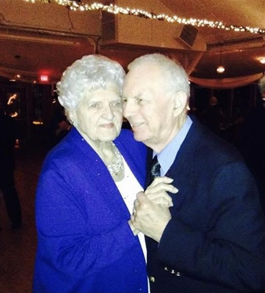 An elderly couple shares a slow dance in soft lighting during an evening celebration.