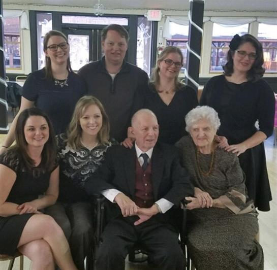 A group of eight family members posing happily together in a community center.