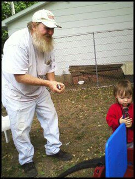 An elderly man interacts with a young child in a backyard setting, fostering playful bonding.