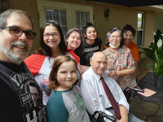 A group of family members of various ages share joyful moments outside a home.