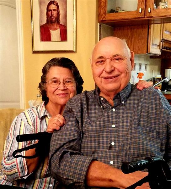 Couple smiles warmly together at home, surrounded by family photos and a cozy atmosphere.