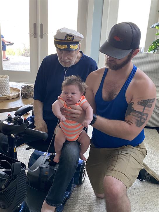 Family members enjoy quality time as one holds a baby while two others watch joyfully outside.