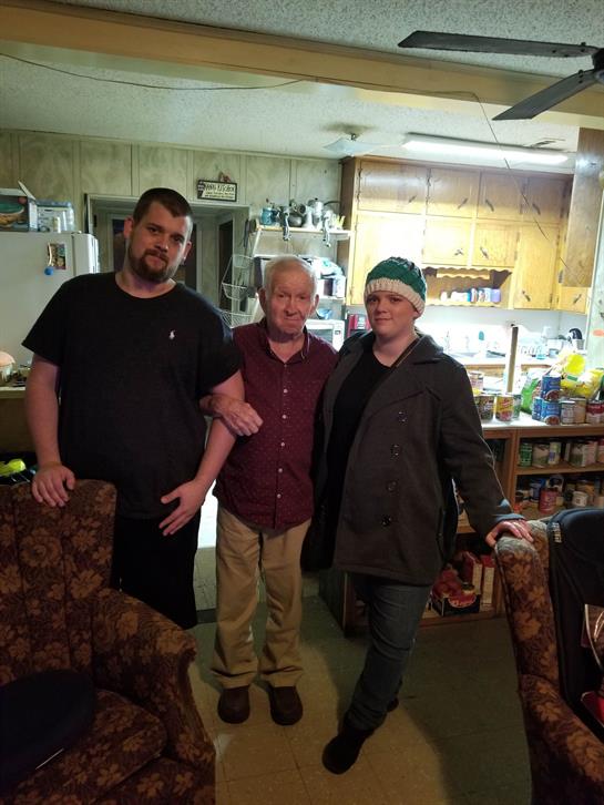 Three people relax together in a warm and welcoming living room filled with vintage decor.