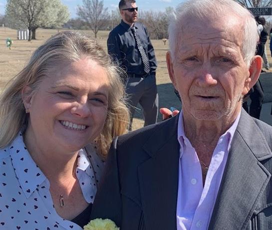 Two people smile together at a park event while enjoying the warm spring weather and company.