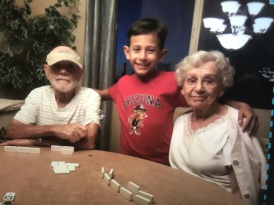 Three family members gather around a table, enjoying a lively game of dominoes together.