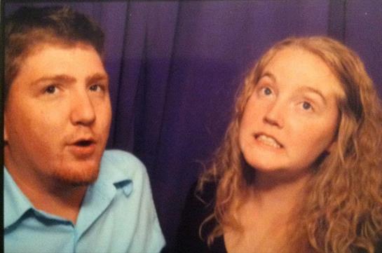 Two individuals make silly faces in a photo booth, enjoying their time together at an event.