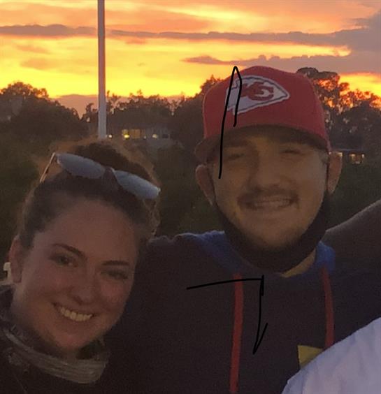 Two friends smile together as they celebrate during a colorful sunset gathering outdoors.