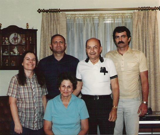 A group of five family members poses together in a living room filled with nostalgia and love.