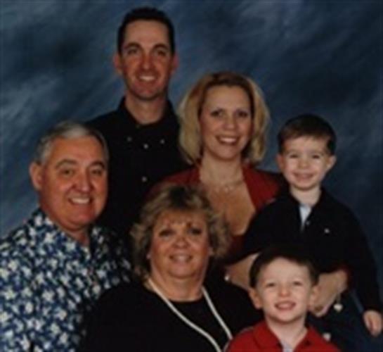 A happy family poses together in a studio, smiling for a formal gathering.